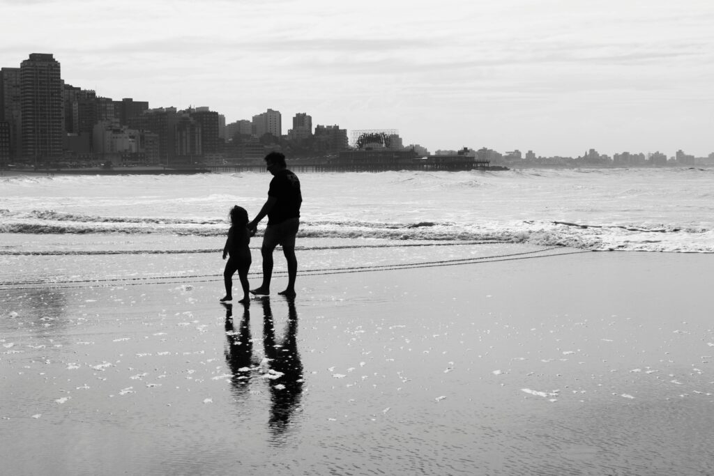 Silhouette of a father and child walking on the beach in Mar del Plata, Argentina.